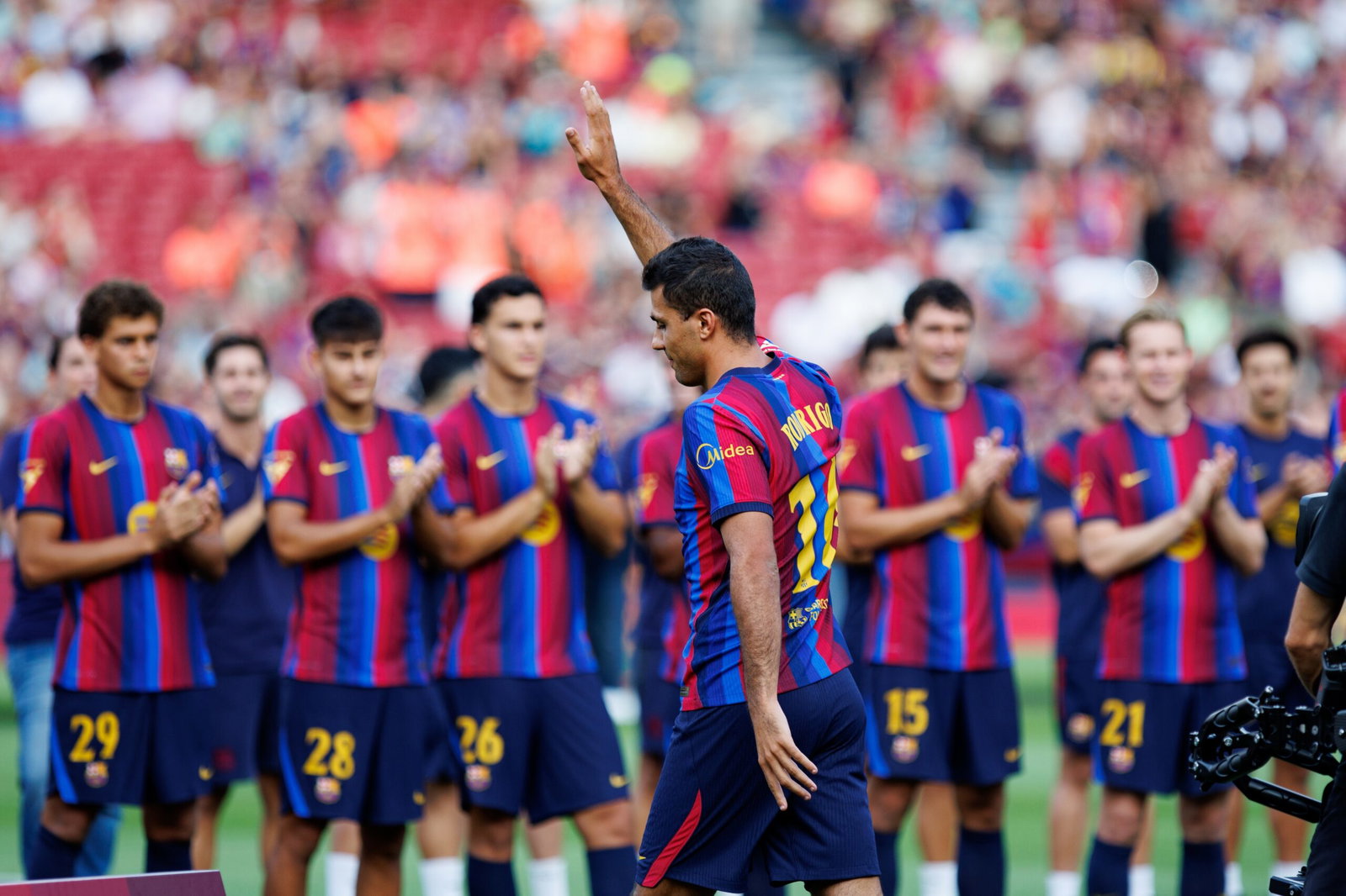 Image of Rodri waving in front of Barcelona teammates